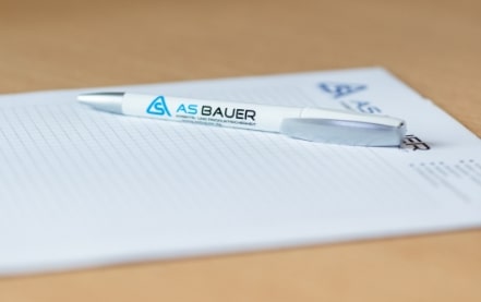 Nahaufnahme Kugelschreiber mit AS Bauer Logo liegt auf Notizblock